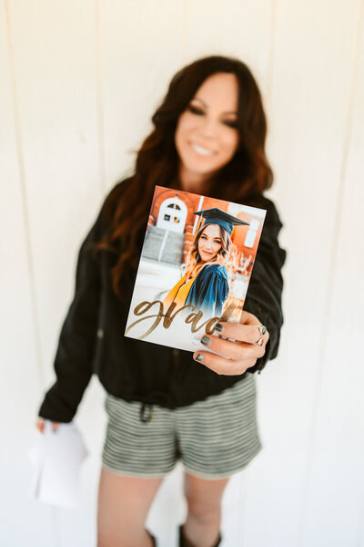 Photographer Annie Bee Photographer at the Sycamore Venue in Flagstaff holding a graduation announcement.