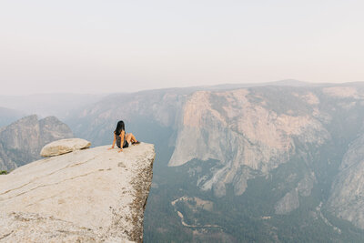 girl sitting on the tip of a rock looking out over Yosemite valley