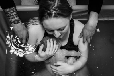 zwart wit foto van pasgeboren baby in handen van moeder