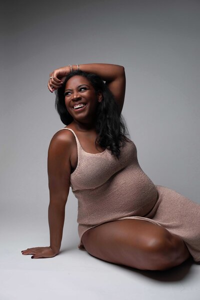 Los Angeles Luxury Maternity Photographer - Expecting Mom Smiling while sitting posed on the ground
