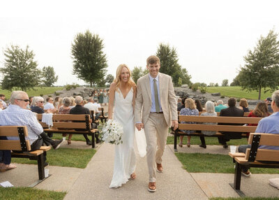 Newlyweds holding hands and walking down the aisle, smiling