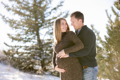 Pregnant wife and husband posing for a photo in one of Denver’s many city parks