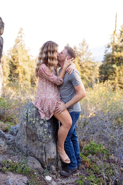 Engaged couple kissing in the woods