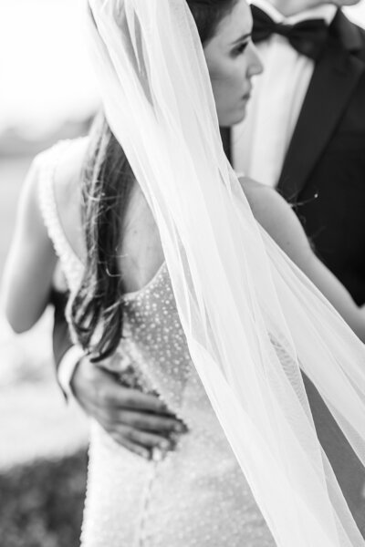 Bride holding champagne in floral lace robe in front of bridal gown in San Marcos.