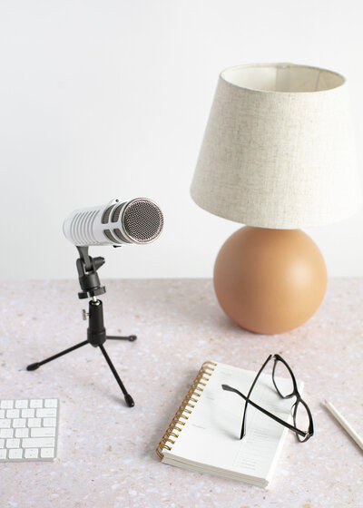 Podcast mic next to a lamp and notebook