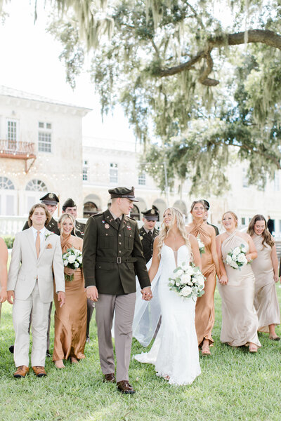 groom in uniform holding hands with his bride