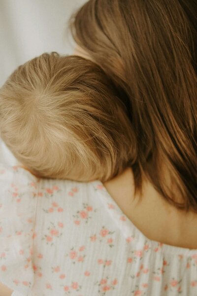 Image of a mother holding a child, photograph taken from behind