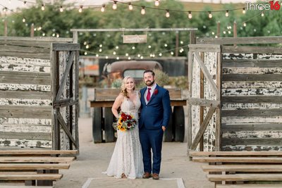 Bride and Groom pose together outside the open rustic gates at the Peltzer Winery wedding venue in Temecula