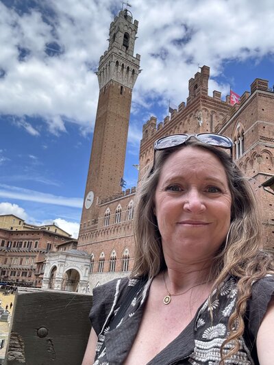 Terra from Adventures by Terra standing in Piazza del Campo in front of the Torre del Mangia, in Siena, Italy