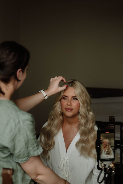 toowoomba Gabbinbar bride placing her earrings under her beautiful wavy hair, natural makeup