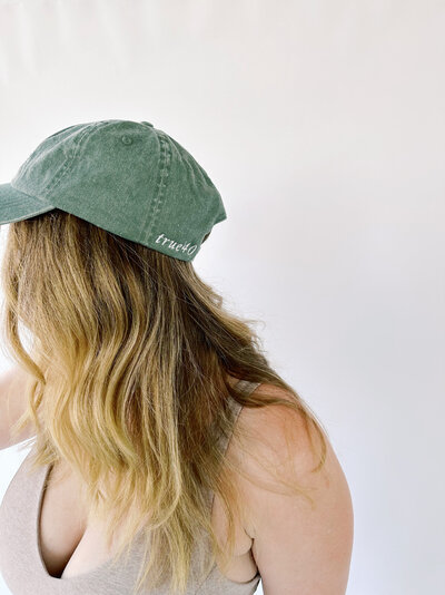 Woman wearing green baseball cap with embroidered True40 logo on the side