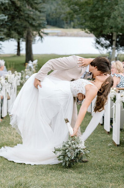 bride and groom kiss in the aisle at their wedding ceremony