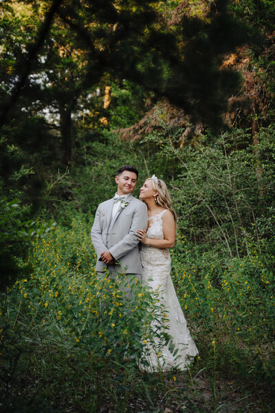 A couple stands together in a lush, green outdoor setting, showcasing the natural beauty and romantic ambiance of an outdoor wedding.