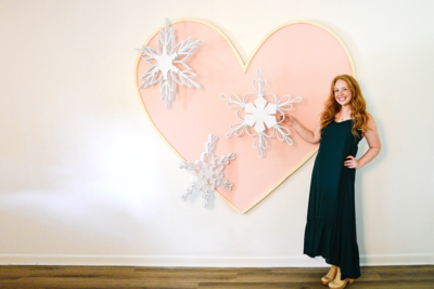 Christmas designer posing with a giant snowflake and heart