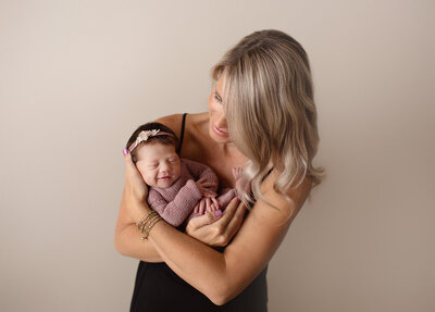 photo of denver newborn photographer holding a baby girl in the studio
