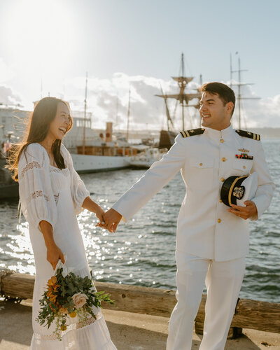 bride and groom walking by bay