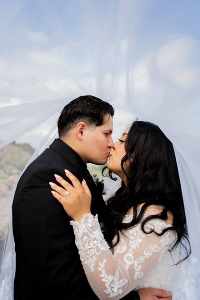 bride and groom kiss under the veil at a waterfront in Dubuque IA