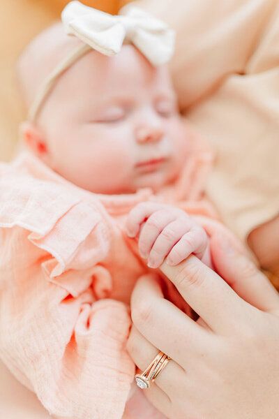 Detail image of baby's hand grasping her mother's finger