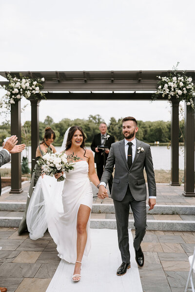 Elegant wedding ceremony arch adorned with lush greenery and white roses by Leigh Florist, creating a romantic backdrop for vows.