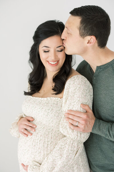 a man kissing his pregnant wife on the head