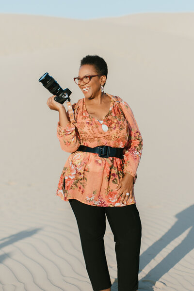 black woman holding camera while smiling and looking to the side