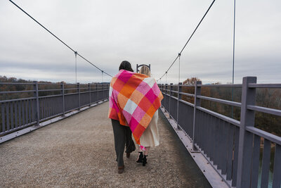 Wives walk across a Tennessee bridge with a lesbian flag blanket draped over their shoulders