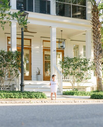 A little boy wearing a Peter Pan collared jumper having his milestone session in front of a white house in Palmetto Bluff by a Palmetto Bluff photographer in Bluffton, South Carolina.