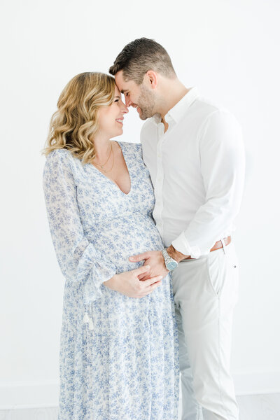 Parents-to-be embrace and smile during maternity portrait session