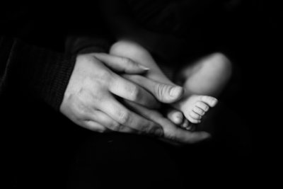 mom and dad's hands holding baby feet