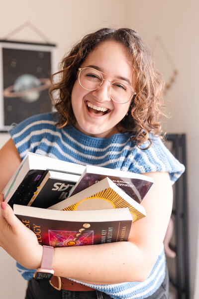 woman smiling and holding a stack of books on top of her head