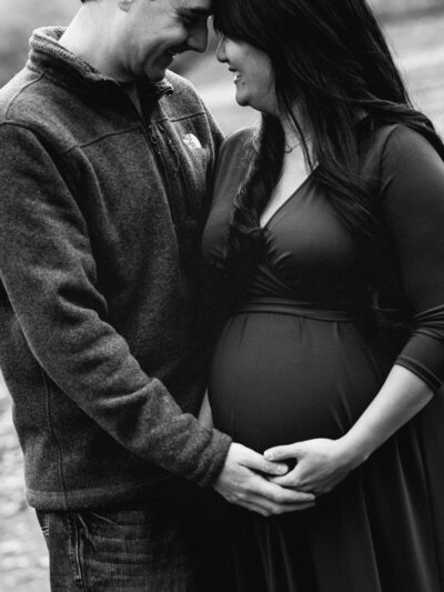 husband and wife holding belly for maternity photos