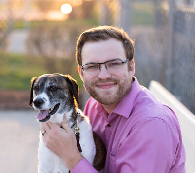 Amy Hord's husband, Brandon Hord, smiling and holding their dog, Rosie.