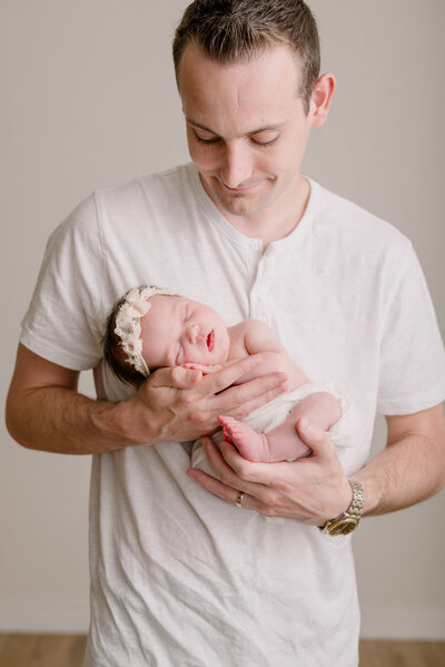 Newborn baby swaddled in a white wrap with a cute headband on.