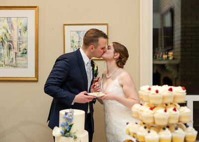 bride and groom kissing after sharing a piece of cake