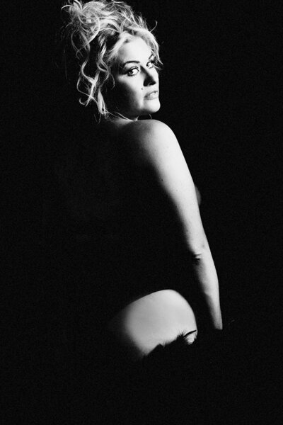 A dramatic black and white image of a blonde woman in black lingerie.