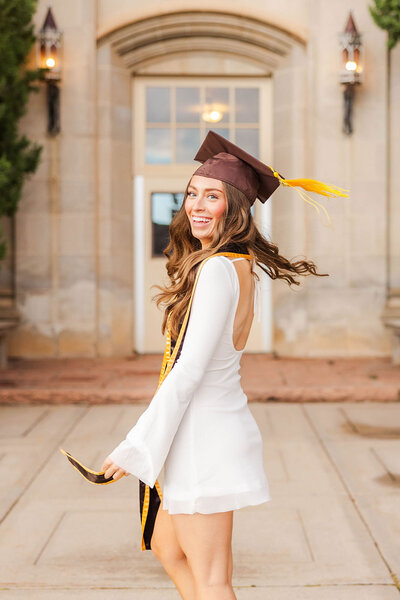 College graduate posing for her graduation photos at the University of Wyoming campus. 