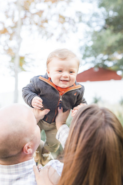 family holding smiling son in the air
