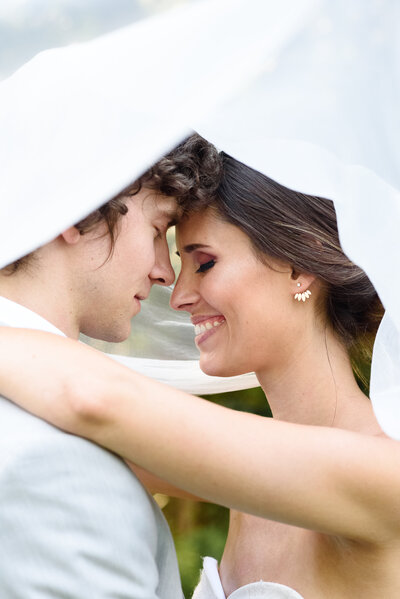 smiling couple under bridal veil