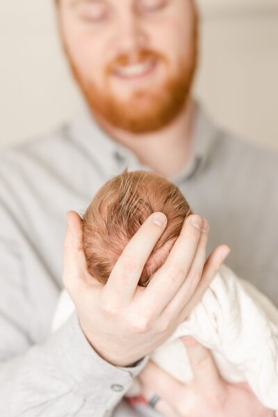 dad holding son's head for newborn photo