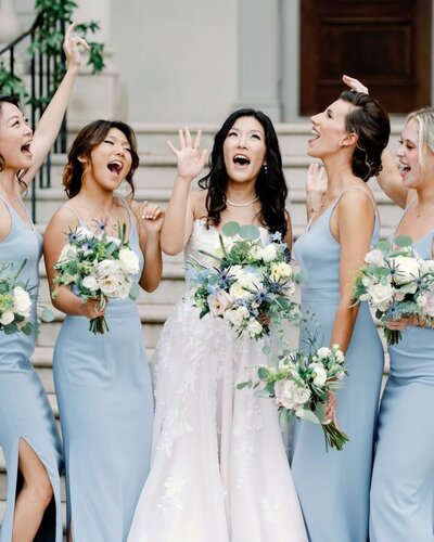 Bridesmaids wearing blue sing with bride on her wedding day.