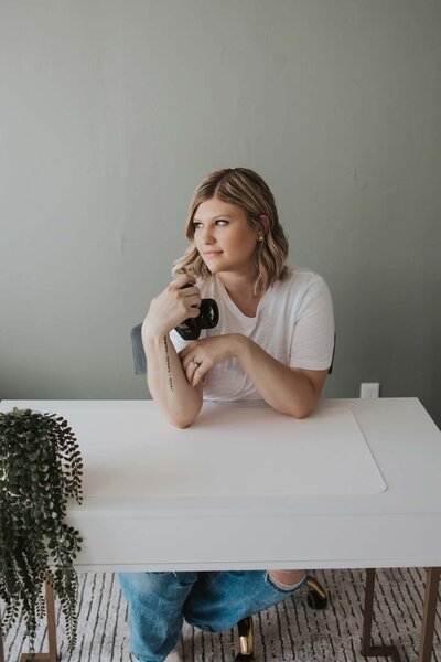 A woman is looking left with a camera in her left hand.