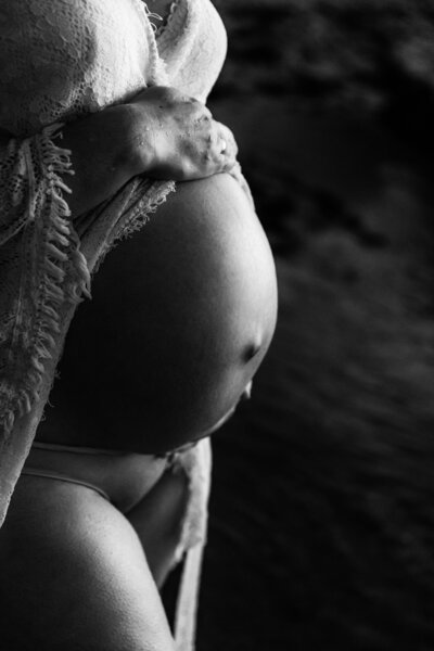 Black and white close up image of exposed belly with hands