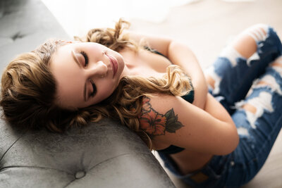 woman with tattoos leaning on couch looking down