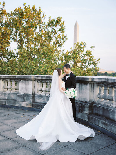 Bride and groom share a kiss with the Washington Monument in the background during their elegant and classic wedding at DAR Constitution Hall in Washington, D.C., planned by Blue Sapphire Events.
