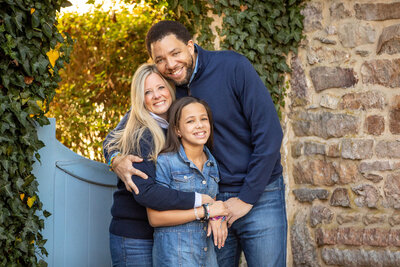 a family of three during an outdoor family session they are all wearing blue. 