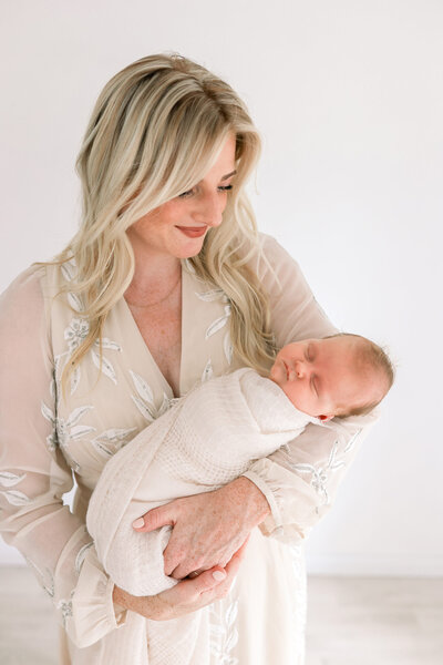 Die Babyfotografin Bielefeld Josephine Böck schmückt ihr Fotostudio in Paderborn mit Neugeborenenfotos und Babyfotos aus Gütersloh. Sie trägt ein langes cremefarbenes Kleid, welches aus bei den Babyfotoshootings von Mamas getragen wird. Die Familienfotografien sind in stilvollen goldenen Rahmen gerahmt.