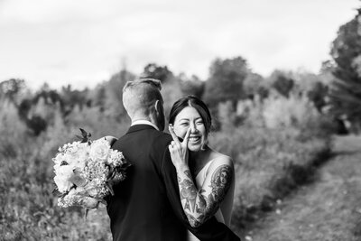 Black and white image of bride hugging groom while holding up a peace sign