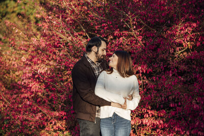New Jersey Botanical Garden | Couple hugging amid red fall foliage during engagement shoot | Ringwood, New Jersey