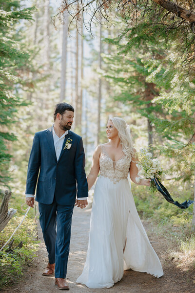 Mountain elopement in Wyoming with bride and groom holding hands and looking off at each other