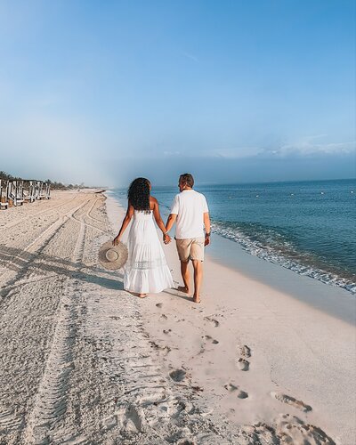 Couple holds hands and walks along the beach in Cancun